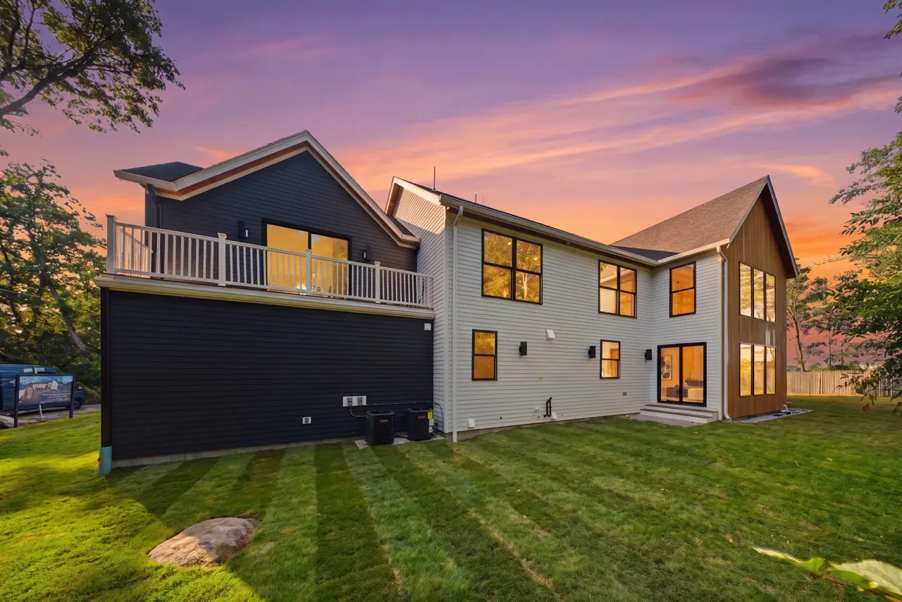 A modern farmhouse in Nahant at sunset, seen from the back lawn.